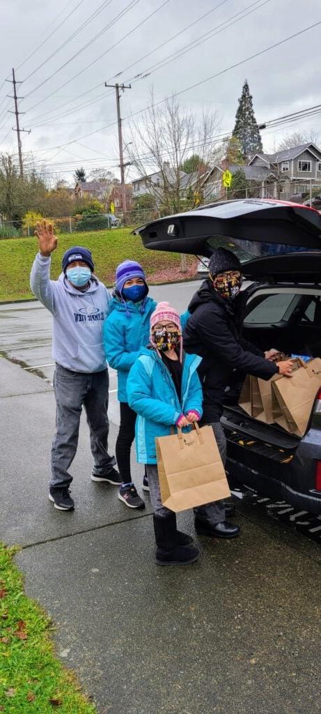 Volunteer parent and her children taking groceries from the car